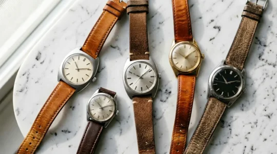 Composition épurée montrant plusieurs montres vintage de petite taille disposées de manière artistique sur une surface minimaliste