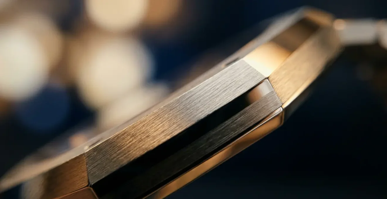 Détail ultra macro d'un hublot octogonal évoquant la Nautilus, avec reflets dorés sur surface brossée et bokeh lumineux