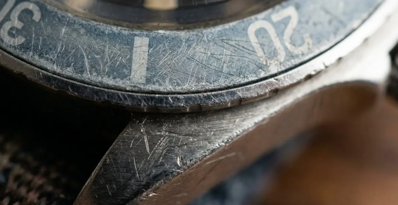 Détail macro d'une lunette de montre vintage avec patine naturelle et décoloration
